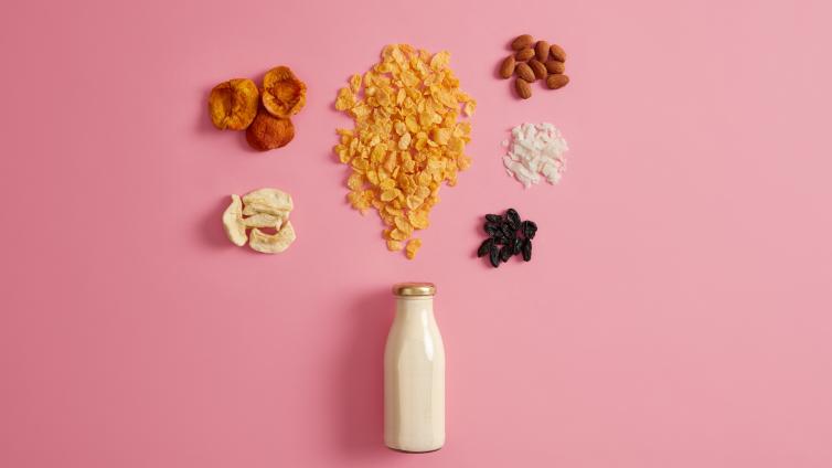 5 separate piles of fruits, nuts, and one bottle of milk on a solid color background