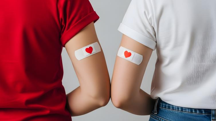 Illustration of the back of two people sitting, their arms have small bandages with a heart icon.
