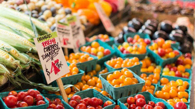 Tomatoes and corn and other vegetables displayed on a table a farmers market 