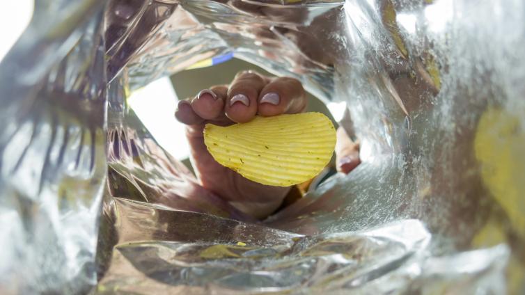 Hand reaching into a bag and pulling out a chip