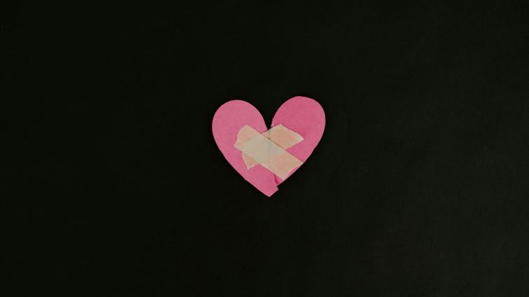 Pink heart ripped in half with tape over it to hold it together